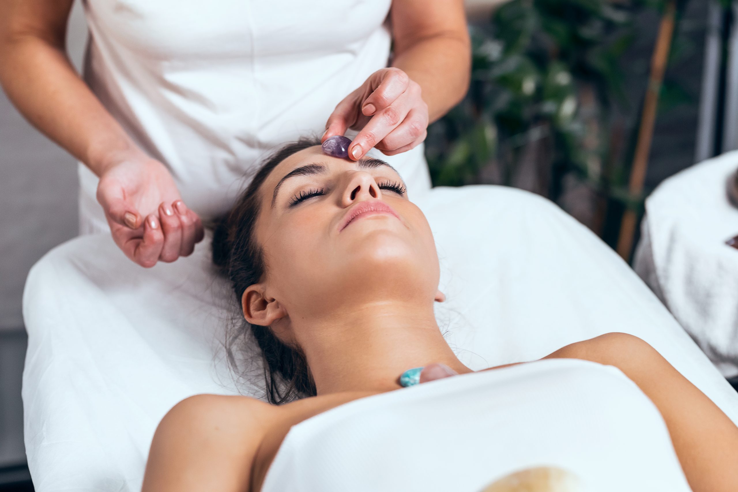 Shot of beautiful young woman having reiki healing treatment in health spa center
