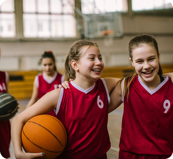 Youth girls basketball team walking off the court together happily.