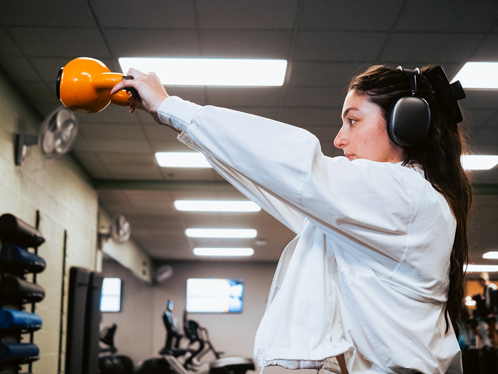 Woman working out with kettle bell in weight lifting facility 